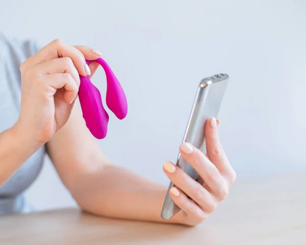 한 여성이 스마트폰으로 자신의 비디오 블로그에 현대의 곡선질 진동 장치를 선보였다. 소녀가 성적 인 장난감에게 조언 한다. — 스톡 사진