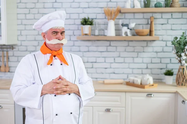 Portrait d'un chef âgé avec une moustache grise touffue dans la cuisine. — Photo