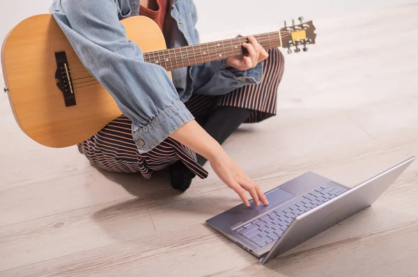 Junge Hipsterfrau beim Anschauen von Gitarren-Tutorials am Laptop. Musik im Fernstudium in Quarantäne — Stockfoto