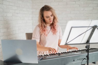 Uzaktan müzik dersleri. Şarkı söyleyen bir öğretmen dersi web kamerasına kaydediyor..