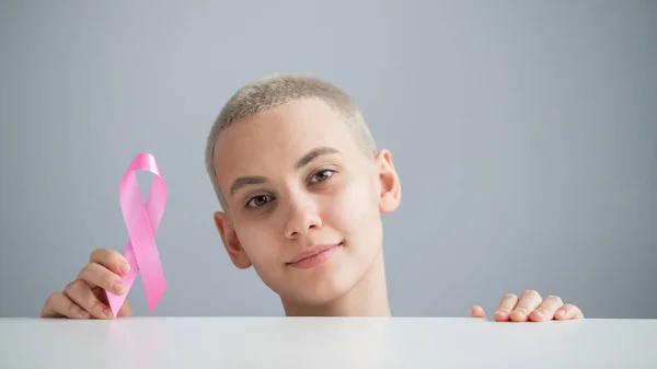 Mulher jovem com fita rosa em um fundo branco. Cancro mamário — Fotografia de Stock