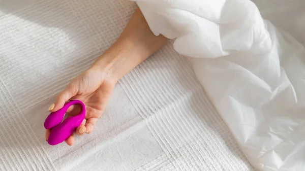 A faceless woman lies in bed under a blanket holding a clitoral vaginal vibrator. The girl masturbates — Stock Photo, Image