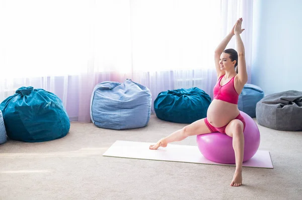 Krásná těhotná žena dělá cvičení na fitness míč. Očekávající matka v posledním trimestru dělá jógu. — Stock fotografie