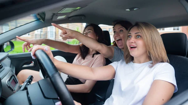 Tre vänner åker på en resa. Kaukasiska kvinnor kör i en bil och pekar finger i överraskning. — Stockfoto