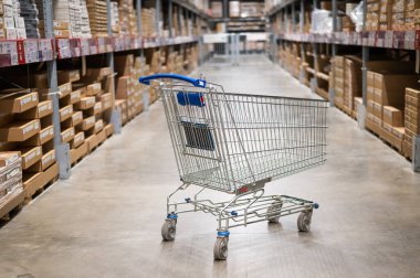 Mobilya deposunda boş bir alışveriş arabası. Kutu rafı soyut bulanık arka planla süpermarket alışveriş sepeti koridoru