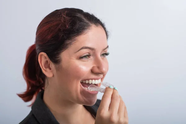 Κοντινό πλάνο μιας γυναίκας που βάζει διάφανα πλαστικά δοχεία. Το κορίτσι χρησιμοποιεί μια συσκευή για να ισιώσει τα δόντια της. — Φωτογραφία Αρχείου