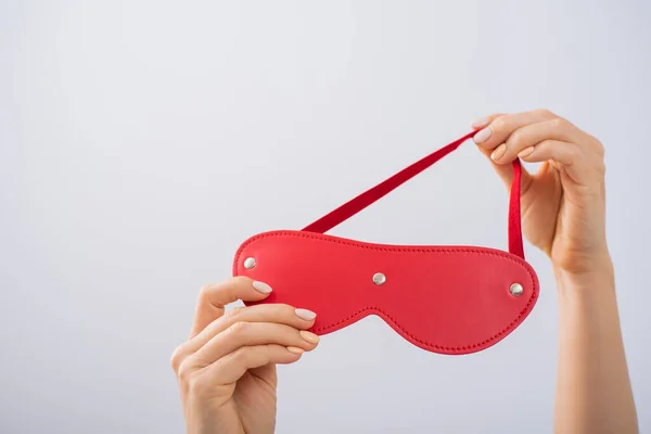 Red leather mask in female hands on a white background. BDSM accessory for women