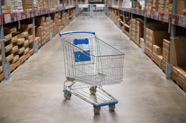 Mobilya deposunda boş bir alışveriş arabası. Kutu rafı soyut bulanık arka planla süpermarket alışveriş sepeti koridoru