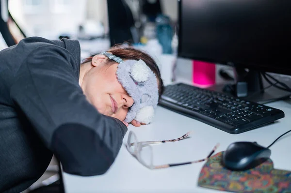 Affärskvinna i mask med förbundna ögon sover på kontoret. Utmattad anställd på arbetsplatsen — Stockfoto