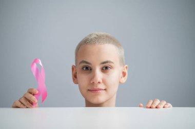 Beyaz arka planda pembe kurdeleli genç bir kadın. Meme kanseri