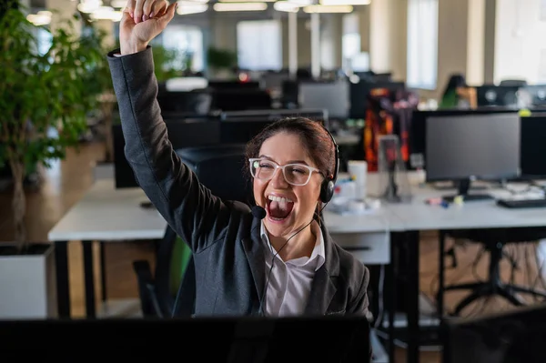 Mujer de negocios se regocija por el éxito laboral. La operadora del centro de llamadas levantó las manos en felicidad en su escritorio —  Fotos de Stock