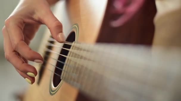 Primer plano de las manos femeninas en una guitarra acústica. La chica aprende a tocar la guitarra — Vídeos de Stock