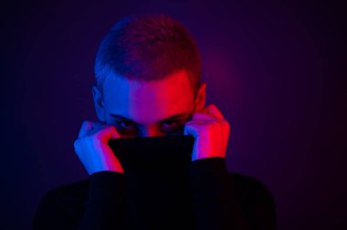 Neon ışıklı kısa saçlı güzel bir genç kadının portresi. Balıkçı yaka giyen bir kız poz veriyor.