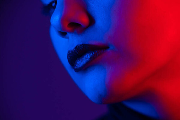 Close-up portrait of beautiful young woman with short hair in neon light. Girl with sensual lips in ultraviolet light