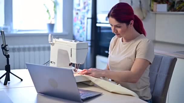 La mujer caucásica enseña, cómo coser a la máquina de coser del vídeo. Educación a distancia — Vídeo de stock