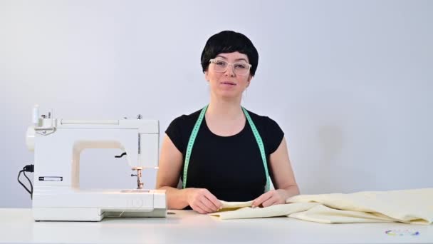 中年妇女在白色背景的电动缝纫机上远程教缝纫. — 图库视频影像