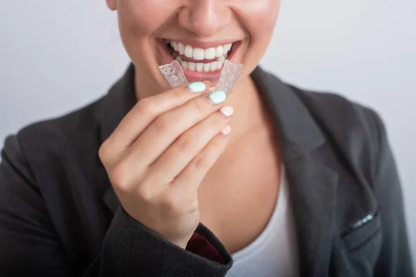 Close-up de uma mulher colocando retentores de plástico transparente. A menina usa um dispositivo para endireitar os dentes — Fotografia de Stock
