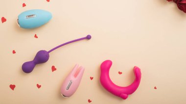 Tatmin etmek için kadın aksesuarlarından düz bir şekilde uzanıyordu. Şeftali arka planda vibratörlerin kalpleri ve gülleri. Boş boşluk