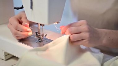 Yakın plan. Bir kadın elektrikli dikiş makinesinin ipliğini kesiyor.