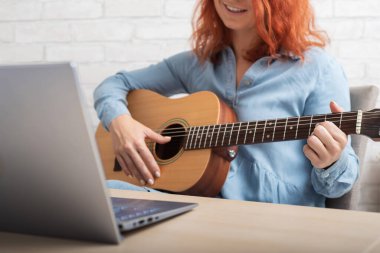 Bir kadın çevrimiçi gitar çalmayı öğretiyor. Dizüstü bilgisayarda uzak müzik dersleri