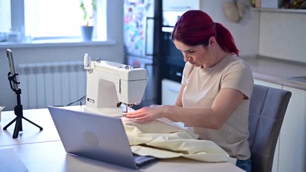 La mujer caucásica enseña, cómo coser a la máquina de coser del vídeo. Educación a distancia — Vídeo de stock