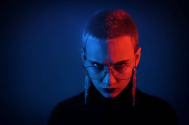Neon ışıklı kısa saçlı güzel bir genç kadının portresi. Hoşnut olmayan kız poz veriyor