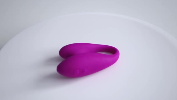 Den klitorala vaginala vibratorn snurrar på en vit platta. En modern sexleksak — Stockvideo