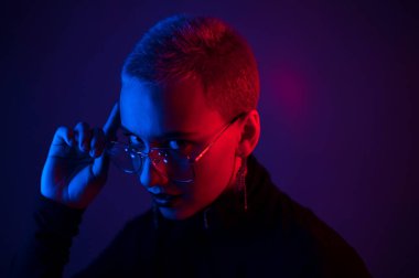 Neon ışıklı kısa saçlı güzel bir genç kadının portresi. Hoşnut olmayan kız poz veriyor