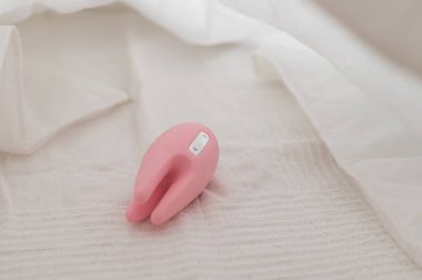 Yatağın üzerinde beyaz bir çarşaf üzerinde klitoral vibratörün yakın çekimi.