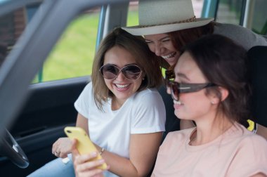 Üç mutlu kız arkadaş bir yolculuğa çıkıyor. Kadınlar arabaya biner, telefona bakar ve güler..