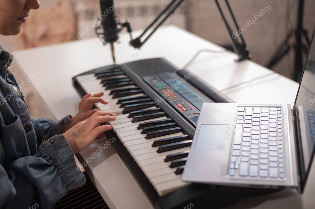 Young woman is broadcasting while playing the electric piano on a white background