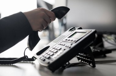 Sabit bir telefondan bir numarayı arayan kadın bir ofis çalışanının eli yakın çekim. Meçhul kadın sekreter telefonda.