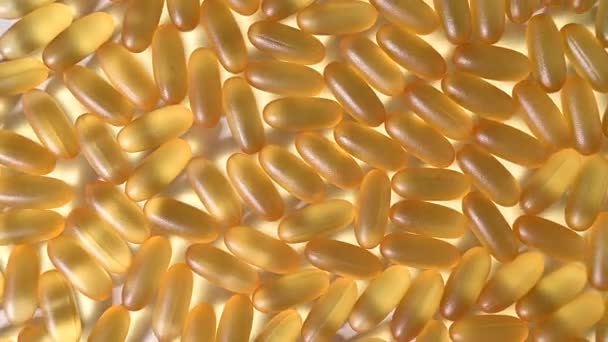 Primo piano di omega dorata tre capsule. Integratore alimentare olio di pesce ruotare su fondo bianco — Video Stock