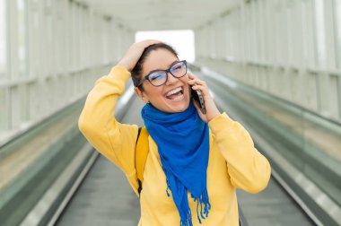 Mutlu kadın travertörün üzerinde duruyor ve cep telefonuyla konuşuyor.