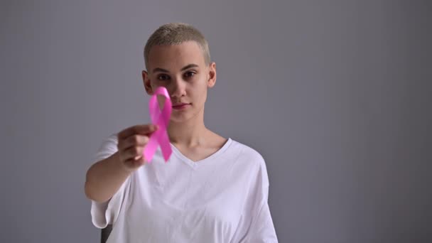 Junge Frau mit rosa Schleife auf weißem Hintergrund. Brustkrebs — Stockvideo