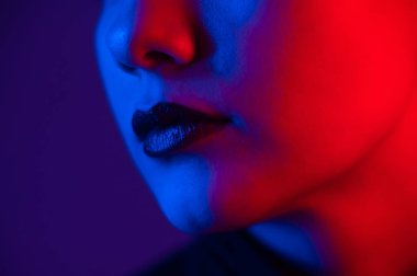 Kısa saçlı, neon ışıklı güzel bir genç kadının yakın plan portresi. Ultraviyole ışıkta dudakları şehvetli olan kız..