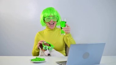 Yeşil peruklu ve neşeli gözlüklü genç bir kadın bira içer ve fındık yer. Bir kız bir köpekle masaya oturur ve Aziz Patrick gününü internetten arkadaşlarıyla sohbet ederek kutlar..