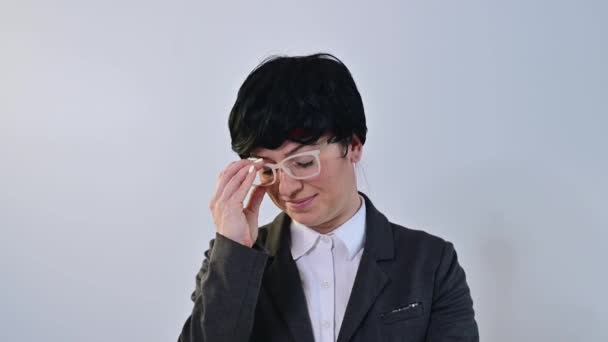 Caucasian woman in suit takes off glasses and wig on white background. — Stock Video