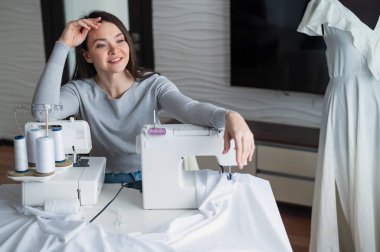 Beyaz kadın evde bir elbise dikiyor. Bir terzinin çalışma alanı