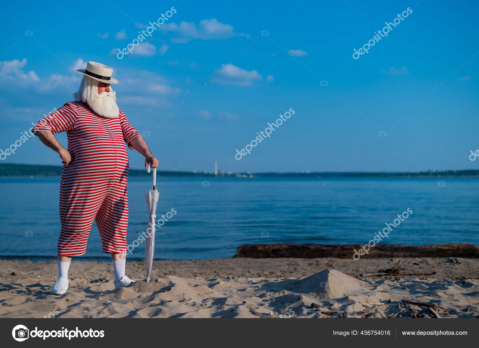 An elderly gray-haired man in a classic bathing suit and hat