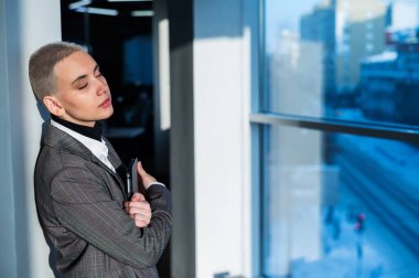 Kısa saçlı düşünceli genç bir kadın ofiste koltukta oturuyor..