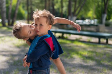 Kız dışarıda kardeşini öpüyor.