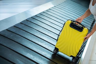 Bir kadın bagaj bandından bir bavul alır..