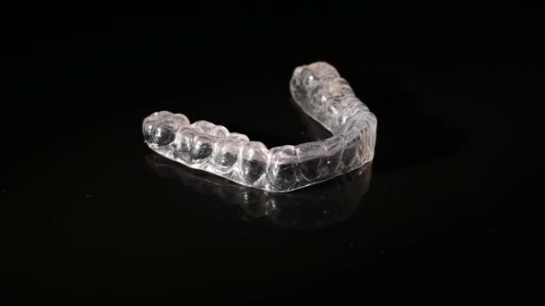 Removable plastic retainers for bite correction revolve against a black background — Stock Video