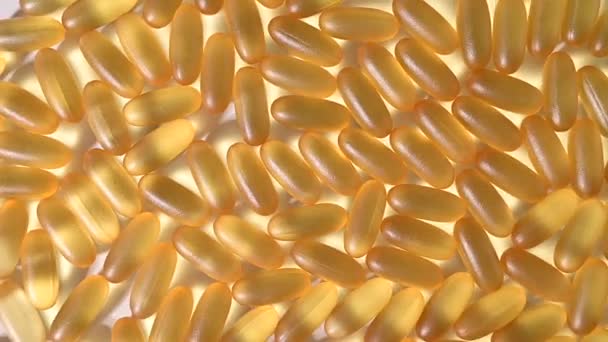 Close-up van gouden omega drie capsules. Voedingssupplement visolie roteren op een witte achtergrond — Stockvideo