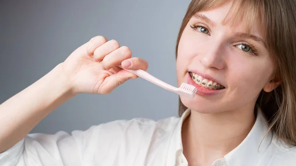 Portrait of a caucasian woman with braces on her teeth holding a toothbrush. — Stock Photo, Image
