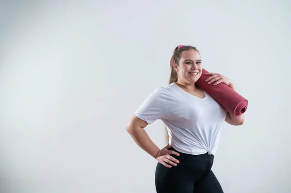 Genç, şişman, beyaz bir kadın elinde paspas tutuyor. Çekici ve spor giyim modeli beyaz arka planda duruyor. — Stok fotoğraf