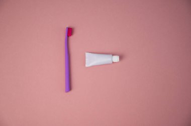 Diş fırçası ve pembe arka planda bir tüp diş macunu. Ağız temizleme ürünleri