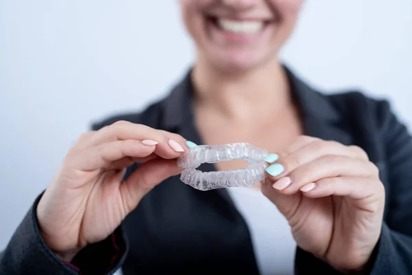 Une femme tient un protège-dents en plastique transparent. Orthodontistes morsure dispositif de correction — Photo