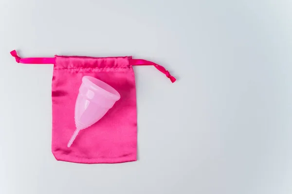 Copo menstrual rosa e saco de seda em um fundo branco. Espaço de cópia — Fotografia de Stock